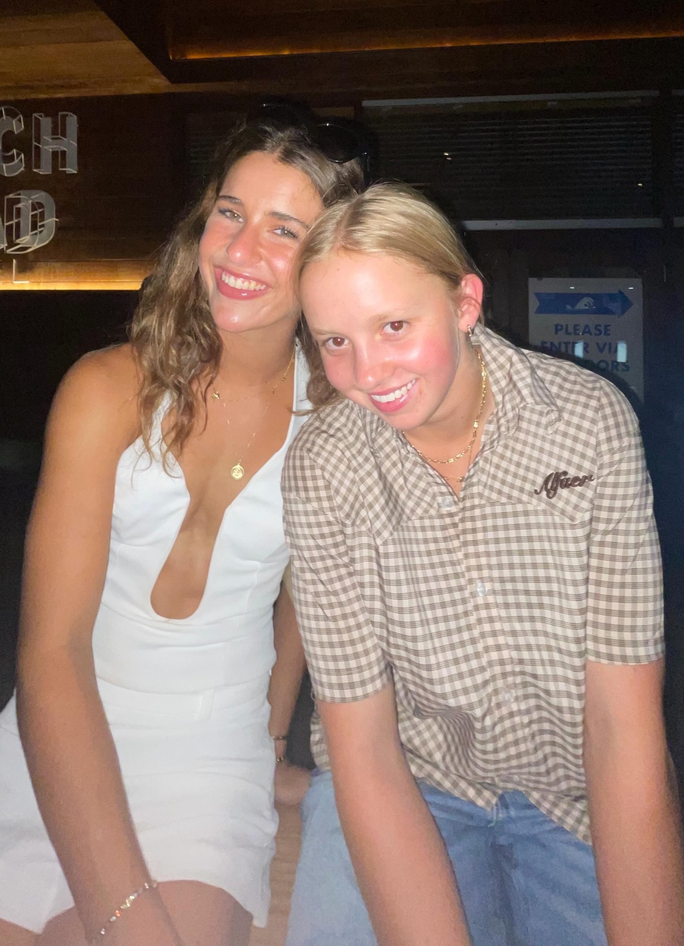 Yas and Soph off-duty, cheek-to-cheek, warm venue light.