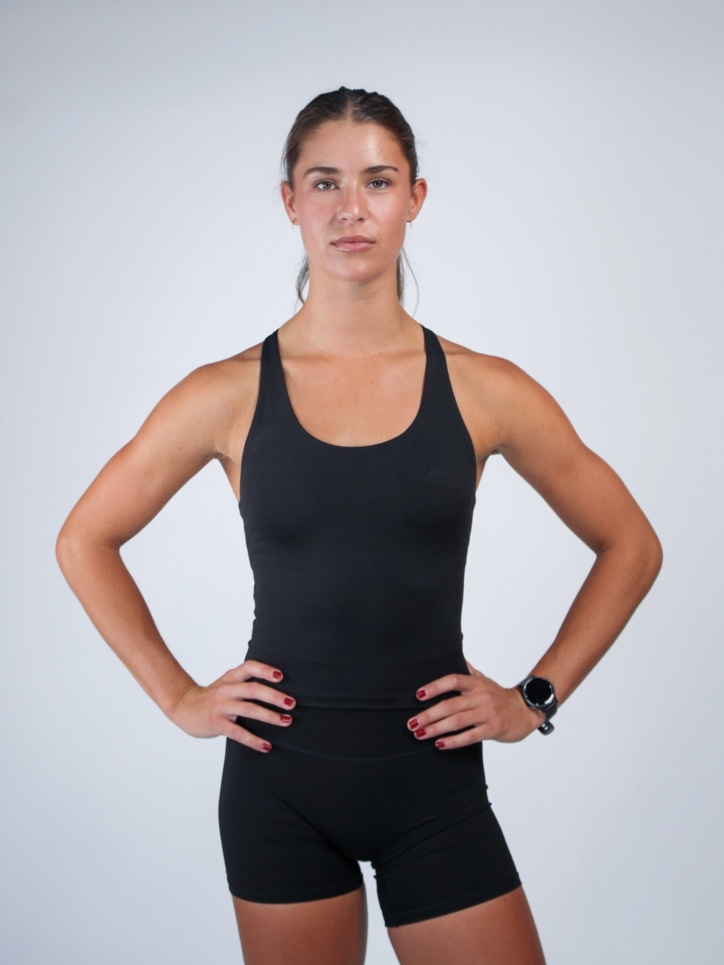 Yas front-on in a black Insync tank — full face, hands on hips.
